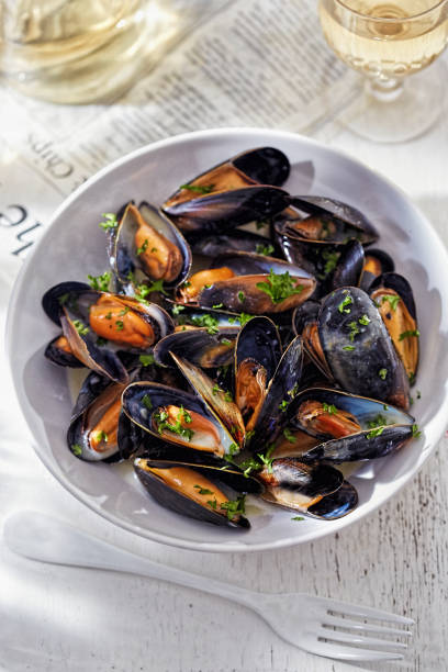 Bowl of mussels in white wine sauce garnished with parsley stock photo