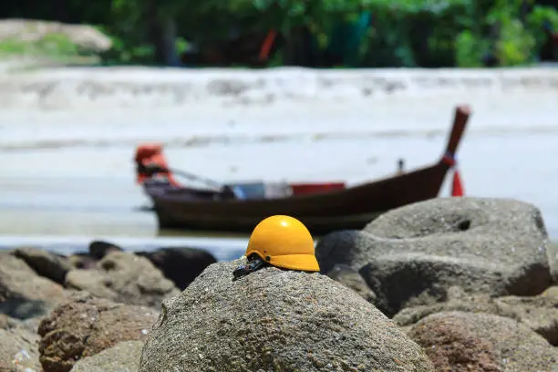 Gondola on the river. River on the beach. Construction helmet on the rocks.