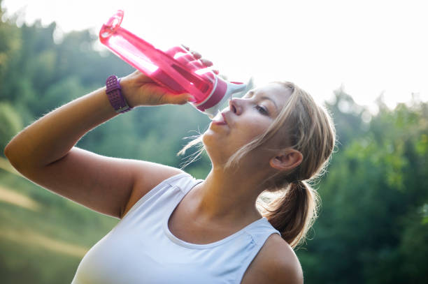 istock Young sportswoman drinking water after run 671956030