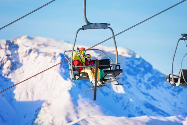 istock Two skiers lifting on lift against snowy mountains 671958936