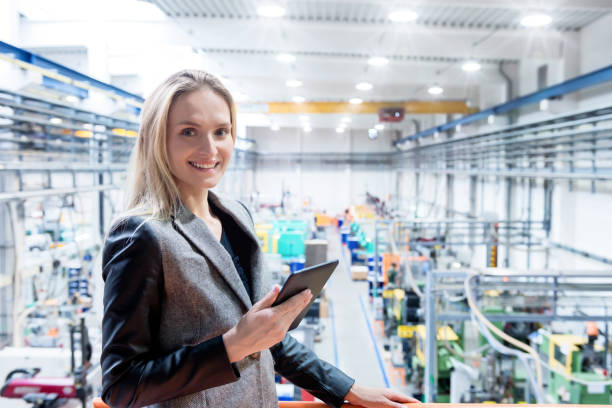 istock Smiling manager & digital tablet & factory 671961708
