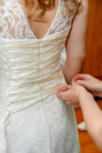 istock Buttoning bride's wedding dress. Close up. 671965132