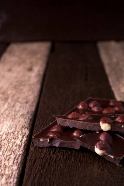 pedaços de chocolate com nozes de avelã em fundo de madeira. - chunky heels - fotografias e filmes do acervo