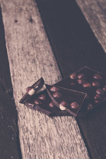 istock Chocolate pieces with hazelnut nuts on wooden background.  Toned photo. 671965186