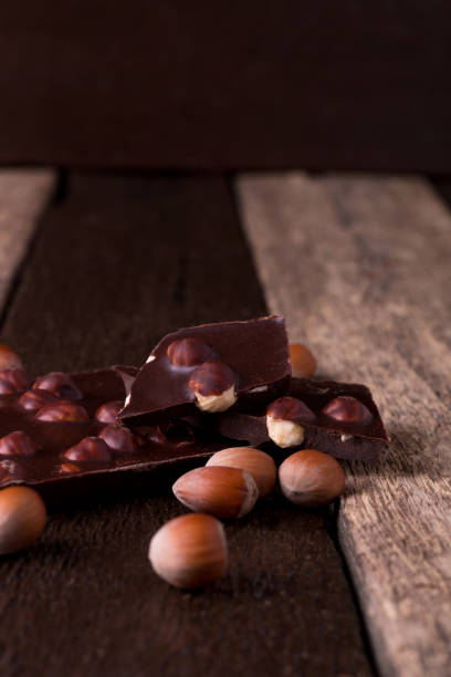 pedaços de chocolate com nozes de avelã em fundo de madeira. - chunky heels - fotografias e filmes do acervo