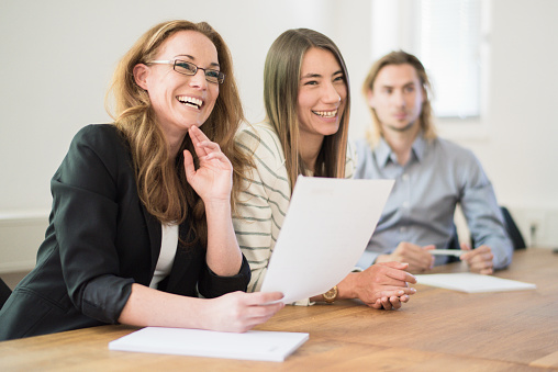 Female Business Manager sitting in Conference Room having a successful Business Meeting together with her two colleagues. Modern Businessmeetings Concept.