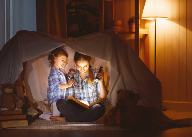 istock mother and child daughter with a book and a flashlight before going to bed 671968262