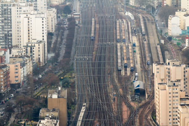 Metro tracks stretching toward the Paris skyline at twilight with traffic roads and buildings visible under a moody evening sky