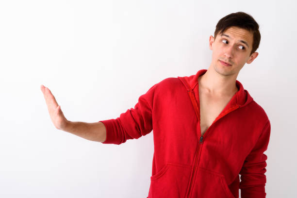 A latin teenage boy raising his hands in front of him and looking at the camera.