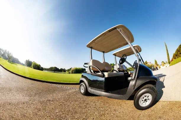 Close-up picture of two golf-carts standing at the car park in summer