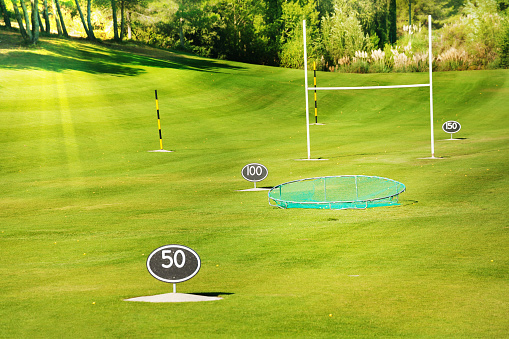 Driving range at golf course with yard signs, flagsticks and balls for practicing swing