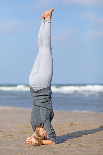 istock Beautiful blonde yoga instructor working out on a daytime beach 672002016