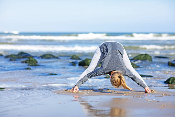istock Beautiful blonde yoga instructor working out on a daytime beach 672002498