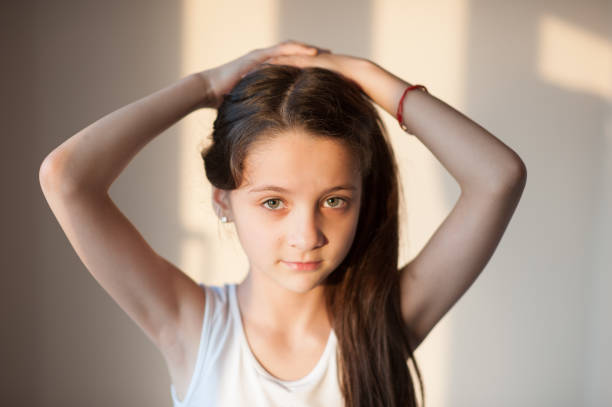 istock adorable young girl doing her hair with both hands 672007986