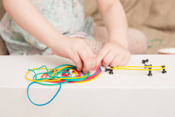 istock Girl builds shapes from colored rubber bands 672008030