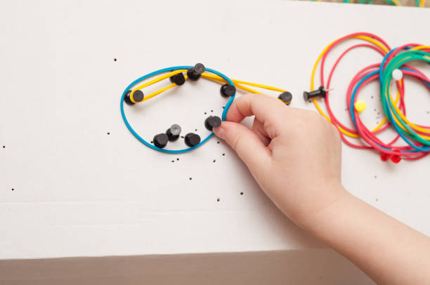 istock Girl builds shapes from colored rubber bands 672008128