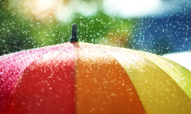 rain drops falling onto umbella with rainbow colour - rainbow umbrella descriptive color multi colored imagens e fotografias de stock