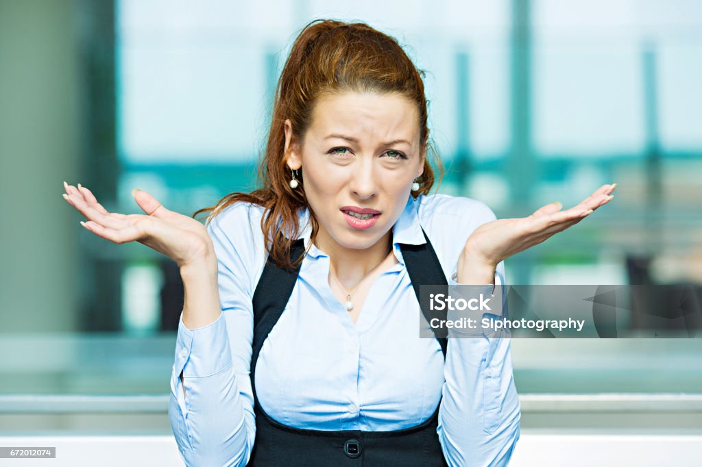 clueless, unhappy young business woman with arms out asking what's problem who cares Closeup portrait clueless, unhappy young business woman with arms out asking what's problem who cares, so what, I don't know, isolated corporate office background. Negative emotions, facial expression Leadership Stock Photo