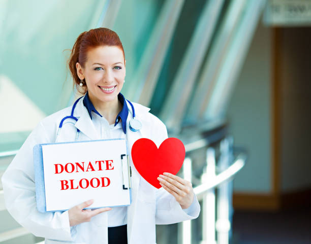 happy smiling female health care professional woman doctor, transfusion medicine specialist holding sign donate blood, red heart - blood bank imagens e fotografias de stock