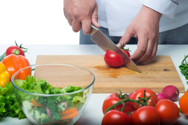 istock cook cuts a tomato for salad on a background of vegetables 672016704