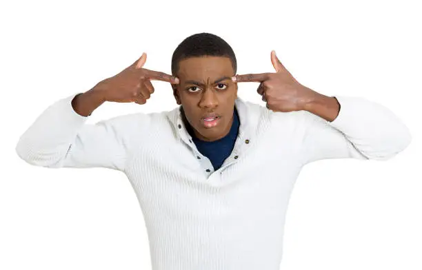 Closeup portrait rude difficult angry young student man gesturing with finger against temple are you crazy? Isolated white background. Negative human emotion facial expression feeling