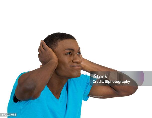 Young Angry Mad Unhappy Stressed Man Covering His Ears Looking Up To Say Stop Making Loud Noise Stock Photo - Download Image Now