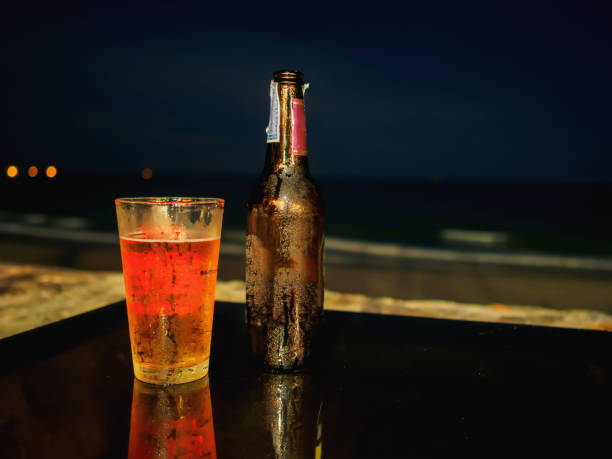 istock Bottle and grass of beer on the table at the beach during night time. 672030236