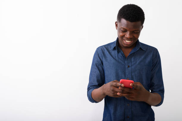 istock Studio shot of young happy black African man smiling while using mobile phone with both hands against white background 672033096