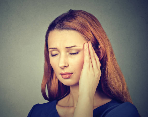 istock woman having headache, migraine isolated on gray wall background 672033628