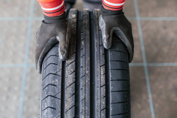 istock mechanic hands pushing a black tire 672033836