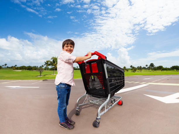 スーパー マーケットのショッピングカートを押して少しヘルパー - luggage cart ストックフォトと画像