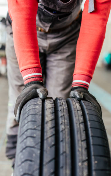 istock mechanic hands pushing a black tire 672036852