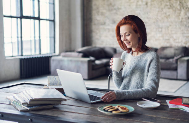 joven mujer utilizando la computadora portátil en un apartamento-loft - break office 30s 20s fotografías e imágenes de stock