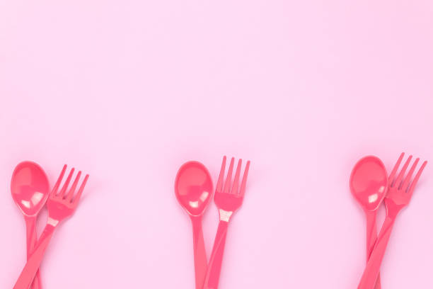 istock Top view colorful plastic spoon and fork on pink table background with copy space. 672041400