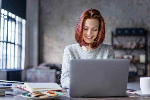 jovem mulher que trabalha em um laptop em um loft - playwright - fotografias e filmes do acervo