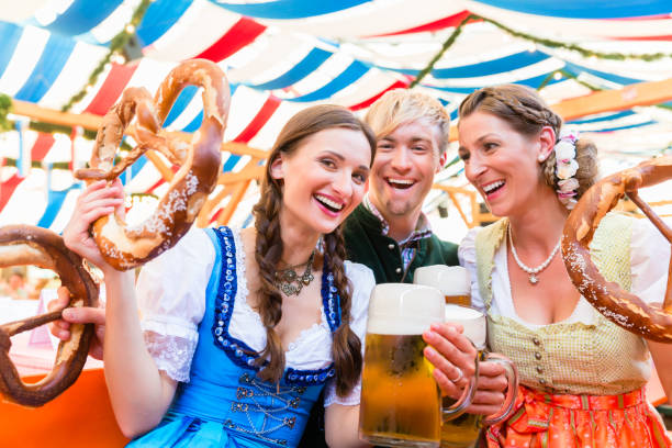 Friends with giant pretzels in Bavarian beer tent Three friends in beer tent at Dult or Beer Fest holding giant pretzels up in the air beer festival photos stock pictures, royalty-free photos & images