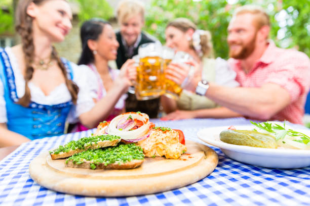 przyjaciele w ogródku piwnym z drinkiem i bawarskimi przekąskami - serving drink beer garden beer glass zdjęcia i obrazy z banku zdjęć