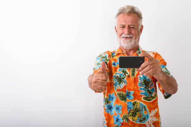 istock Senior Tourist Man Vlogging Using Mobile Phone While Wearing Hawaiian Shirt 672050846