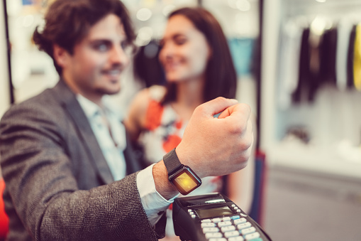 Young man uisng smartwatch in the shop for contactless payment ++++ Note for the inspector: Credit card is fake and is made especially for the photosession ++++