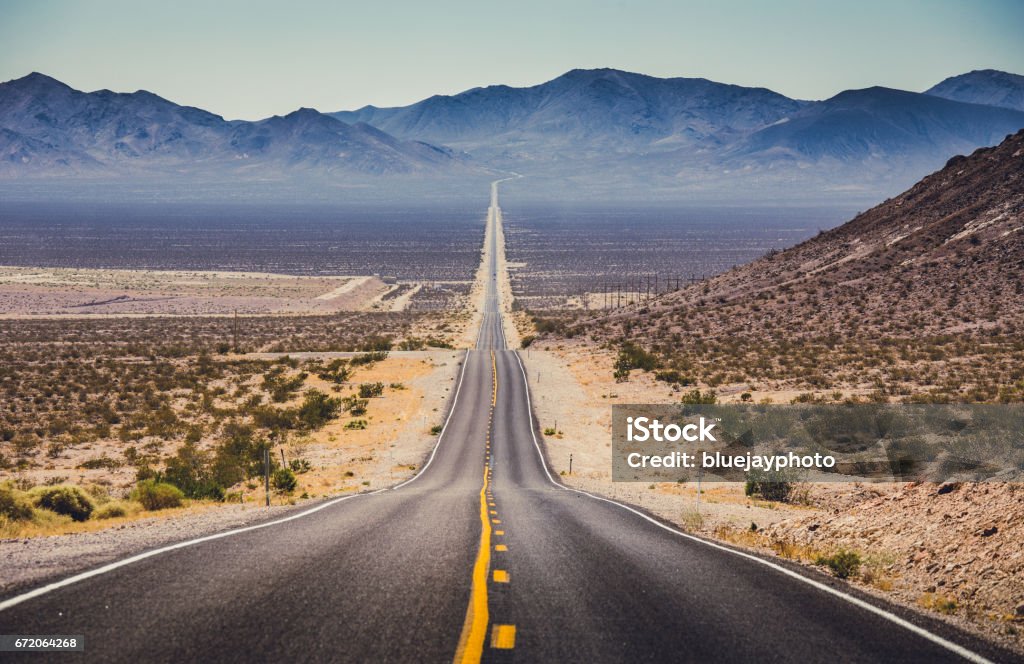 Endless straight road in the American Southwest, USA Classic panorama view of an endless straight road running through the barren scenery of the American Southwest with extreme heat haze on a beautiful hot sunny day with blue sky in summer Death Valley National Park Stock Photo