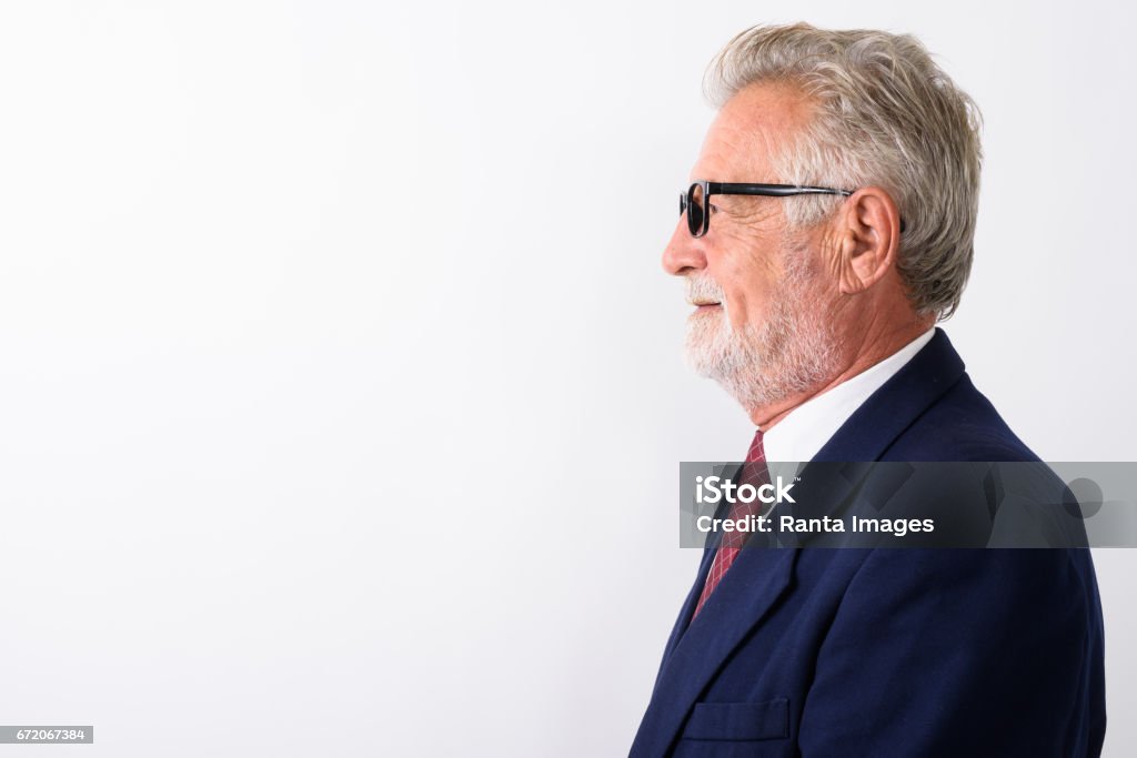 Profile view of happy senior bearded businessman smiling while wearing eyeglasses against white background Profile view of happy senior bearded businessman smiling while wearing eyeglasses against white background horizontal shot Profile View Stock Photo