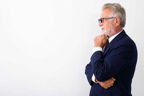 Profile view of handsome senior bearded businessman thinking while wearing eyeglasses against white background horizontal shot