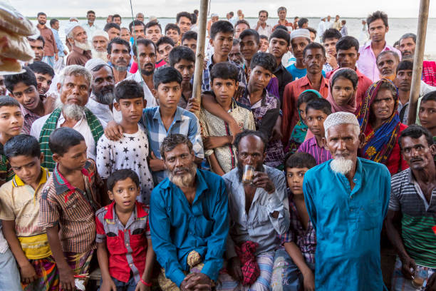 Meghna River, Bangladesh - July 15, 2016: Large group of Bangladeshi people staring intently at the camera at a tea stall Large group of Bangladeshi villagers staring at the camera. They had never seen a foreigner before and were fascinated. Picture taken from inside the tea stall, looking out. india crowd stock pictures, royalty-free photos & images