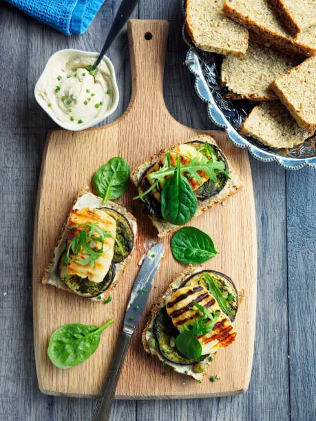 Home made healthy vegetarian open sandwich.grilled aubergine with grilled halloumi cheese and rocket leaves tahini paste,wheaten bread