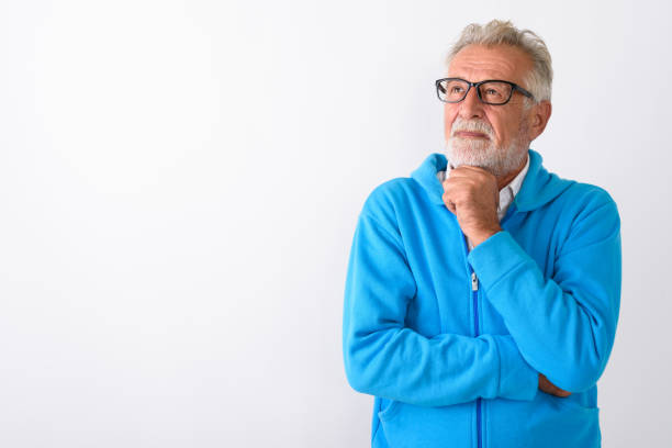 Studio shot of handsome senior bearded man thinking while looking up ready for gym against white background