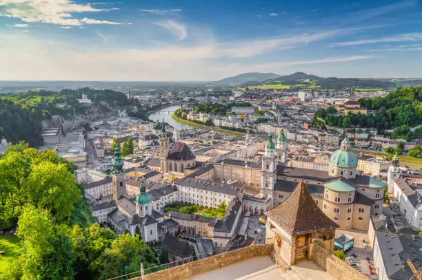 Aerial panoramic view of the historic city of Salzburg with Salzach river in beautiful golden evening light with blue sky and clouds at sunset in summer, Salzburger Land, Austria