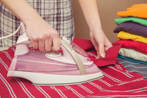 istock Hands with modern iron with steam system ironing clean, crumpled shirt. 672074568