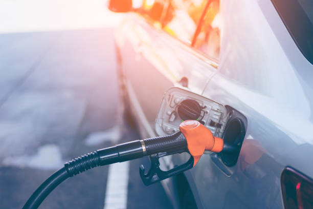 Gas nozzle pumping gas into a gray blonde car