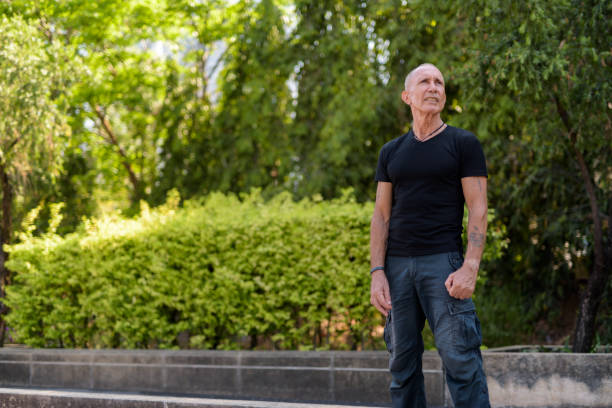 istock Bald senior tourist man standing and thinking while looking up at peaceful park in Bangkok Thailand 672084018