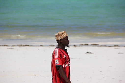 A man walks along a sandy seashore and uses a mobile phone